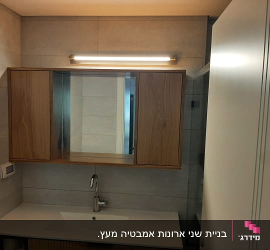 ארון עץ עם מראה ותאורה מעל כיור